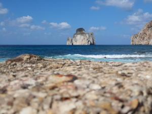una spiaggia rocciosa con una grande roccia nell'oceano di Punta Speranza a Nebida