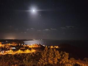 a full moon rising over a town at night at Punta Speranza in Nebida