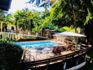 uma piscina com cadeiras e um guarda-sol em ILHABEACH Suítes e Chalés em Ilhabela