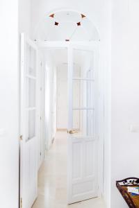 un pasillo con paredes blancas y una puerta abierta en Hispalis Casa Palacio Apartment, en Sevilla