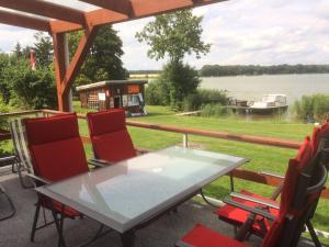 a table and chairs on a porch with a view of a lake at Ferienhaus Am Großen Priepertsee in Priepert
