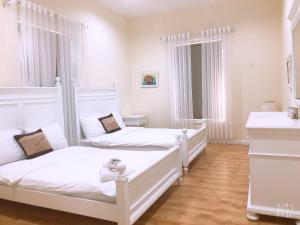 two beds in a bedroom with white walls and wooden floors at LuxSea Villa in Phan Thiet