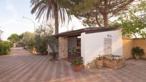 een klein wit gebouw met een palmboom op een binnenplaats bij Villa Calò in Castelvetrano Selinunte