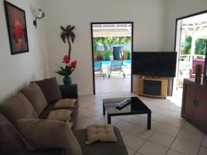 a living room with a couch and a flat screen tv at Villa & Bungalow Fleur de Coco in Sainte-Anne