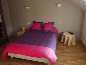 ein Schlafzimmer mit einem großen Bett mit rosa Kissen und einem Tisch in der Unterkunft Chez Lili in Izé