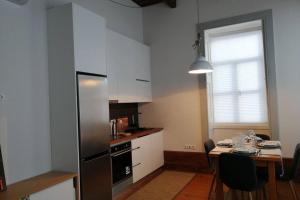 uma cozinha com uma mesa e um frigorífico de aço inoxidável em Ficus Áurea em Aveiro
