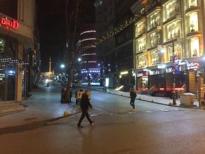 two people walking across a city street at night at Florin Hotel in Istanbul