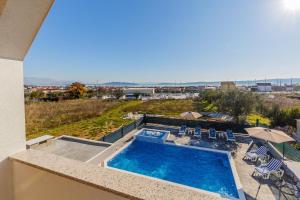 a view of a swimming pool with chairs and an umbrella at VILLA LaMARIN in Kaštela