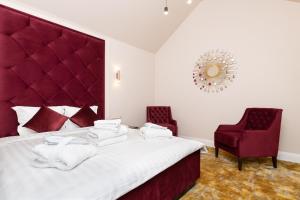 a bedroom with a bed with a red headboard and two chairs at Hotel Meltzer Apartments in Tallinn