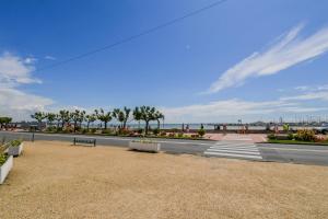 un parc avec des bancs, des palmiers et l'océan dans l'établissement Grain de Sable, à Royan