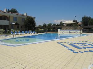 una gran piscina con sillas y un edificio en Villaggio Tulipano, en Bibione