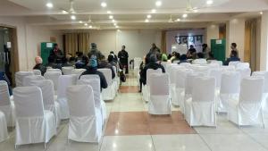 a group of people sitting in a room with white chairs at Hotel Milam Inn in Almora
