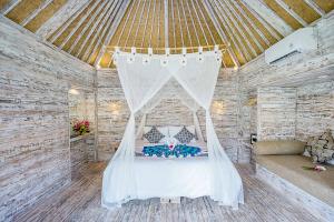a bedroom with a bed with a mosquito net at D'Coin Lembongan in Nusa Lembongan