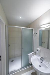 a white bathroom with a shower and a sink at Hotel Onderbergen in Ghent