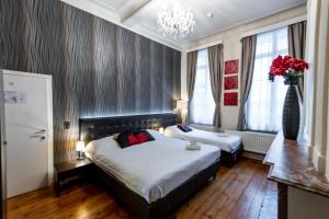 a bedroom with two beds and a vase of red roses at Hotel Onderbergen in Ghent