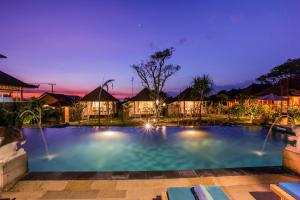 ein großer Swimmingpool in der Nacht mit Häusern im Hintergrund in der Unterkunft D'Coin Lembongan in Nusa Lembongan