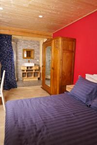a bedroom with a blue bed and a red wall at Le Mazel in Saint-Agrève