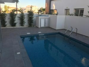 a swimming pool in front of a white wall and a building at Mobina Villas in Larnaca