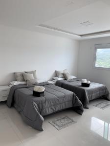 Habitación blanca con 2 camas y sofá en COBERTURA com belíssima vista para o mar e jacuzzi, en Itapema