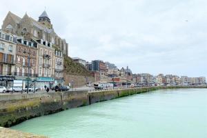 a river in a city with buildings and a bridge at A l'Ancre Bleue in Le Tréport