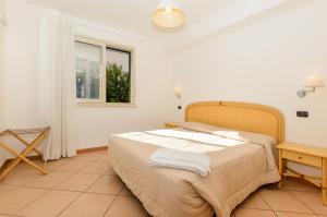 a bedroom with a bed and a table and a window at Le Tartarughe Aparthotel in Letojanni