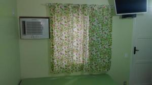 a room with a window with a curtain with flowers at Pousada Luar e Serenata in Conservatória