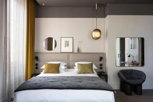 - une chambre avec un lit, un miroir et une chaise dans l'établissement Hôtel de l'Abbaye Lyon - Boutique Hôtel, à Lyon