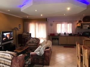 a living room with couches and a tv and a kitchen at Bilene Dream House 1 in Vila Praia Do Bilene