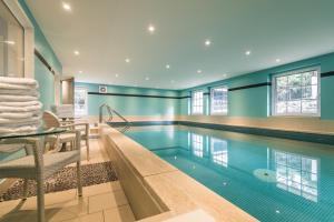 a swimming pool in a house with blue walls at Hotel Norderriff in Langeoog