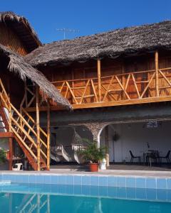 a house with a thatched roof and a swimming pool at Hostal Villa Brisa in Ballenita