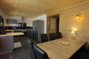 eine Küche mit einem Holztisch mit Stühlen und einem Kühlschrank in der Unterkunft Bottières in Saint-Pancrace