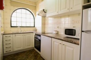 a kitchen with white cabinets and a sink and a microwave at Vau Costa beach apartment with pool in Alvor