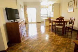 a kitchen and dining room with a table and a television at Vau Costa beach apartment with pool in Alvor