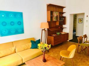 un soggiorno con divano giallo e vaso di fiori di Vintage Design Apartments a Vienna