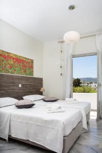 Heart of Paros Apartments في كامبوس باروس: غرفة نوم بيضاء بسريرين ونافذة كبيرة