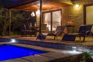 a patio with chairs and a swimming pool at night at Zebra Lodge & Giraffe Lodge in Hoedspruit