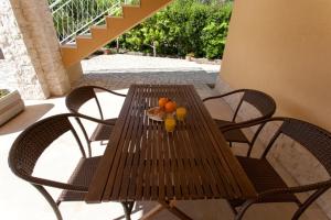 a wooden table with two chairs and oranges on it at Apartments Laura in Krk