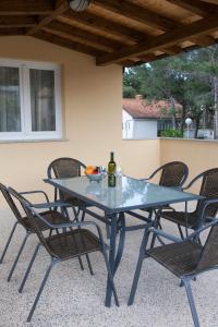 a glass table with chairs and a bottle of wine at Apartments Laura in Krk