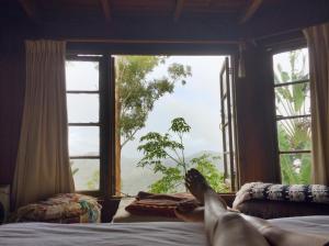 a person laying on a bed looking out a window at The Den of the Treehouse, KINABALU Farm in The Pocket