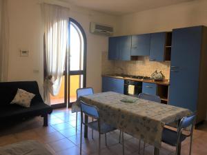 a kitchen with a table and chairs and a kitchen with blue cabinets at Appartamento Il Corallo Blu in Lampedusa +9 photos