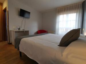 a bedroom with a white bed with a pillow on it at Hotel El Trasgu in Cangas de Onís