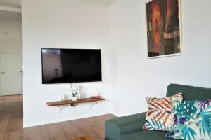 Una sala de estar con un sofá y un televisor en una pared. en Central Port Warsaw Apartment, en Varsovia