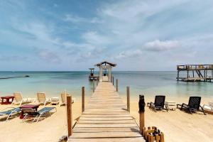 einen Holzweg zum Strand mit Stühlen und einem Pier in der Unterkunft West End Dive Resort in West End