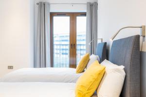 um quarto com uma cama com almofadas amarelas e uma janela em St Albans 2 Bed Luxury City Apartment, 5 mins walk to Train & Allocated Parking em Saint Albans