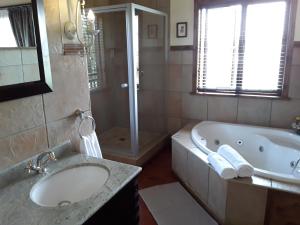 a bathroom with a tub and a sink and a shower at Khumbula Lodge in Underberg +46 photos
