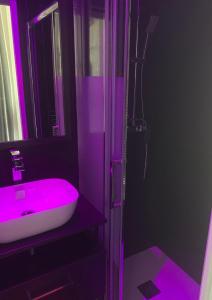 La salle de bains est pourvue d'un lavabo rose et d'une douche. dans l'établissement BAGATELLE NATURISTE HELIOPOLIS clim ascenseur vue mer parking privé, au Cap d'Agde