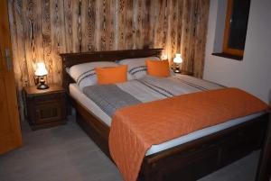 1 dormitorio con 1 cama con almohadas de color naranja y 2 lámparas en Vadszőlős Porta, en Ispánk