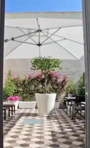 a patio with a large white umbrella and a potted plant at I Colori della Puglia Rooms in Trani