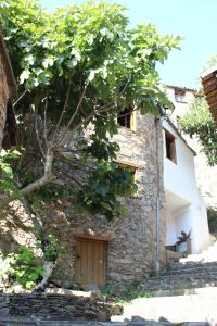 a stone building with a wooden door and a tree at Casa da Carvalha in Lousã