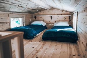 two beds in a room with wooden walls and wood floors at Tiny Homes at Powderhorn Mountain Resort in Mesa